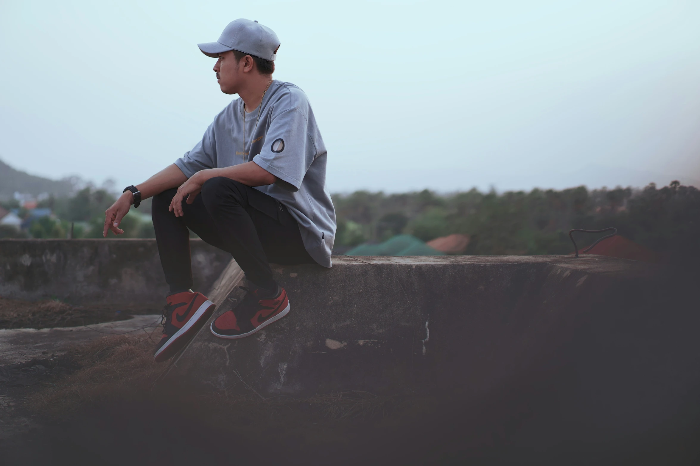 the young man is sitting on the edge of a cement wall