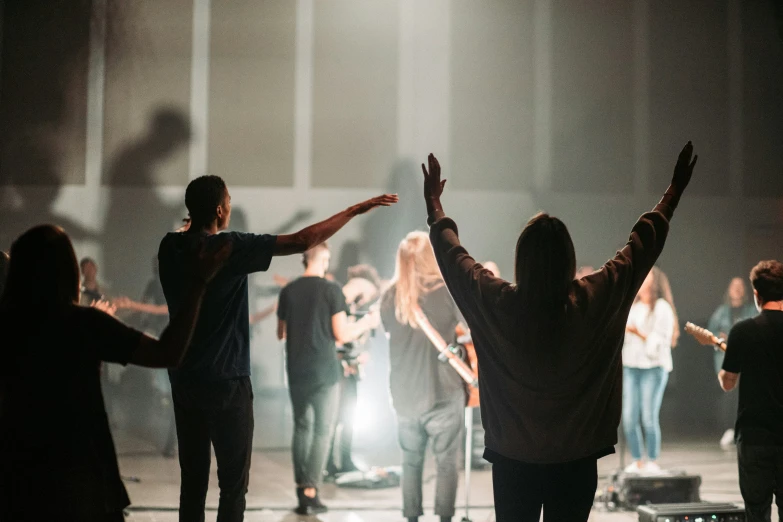 a group of people on a stage with their arms up