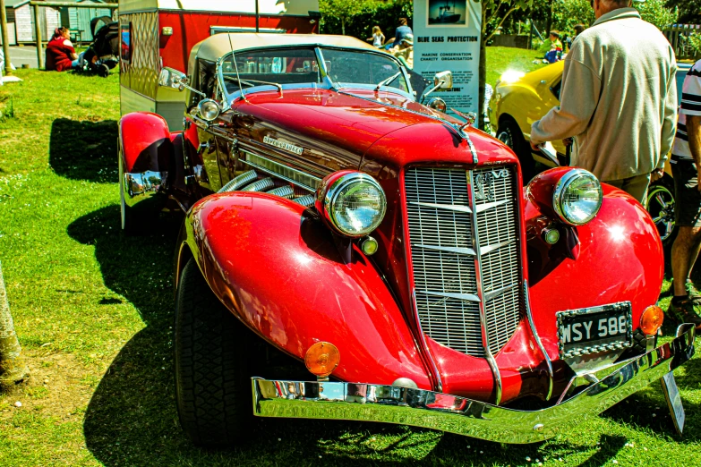 an antique car sits parked on the grass