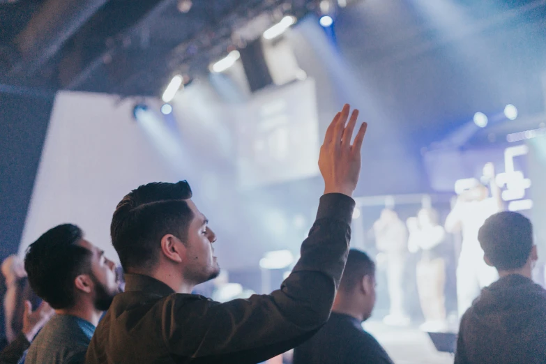 man raising his hands during a performance at an event