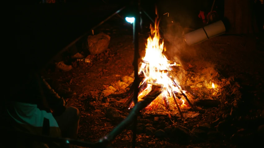 a small fire blazing out at night on a field