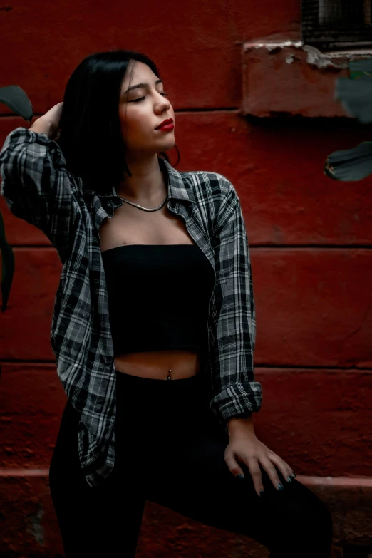 woman in black and white shirt next to a brick wall