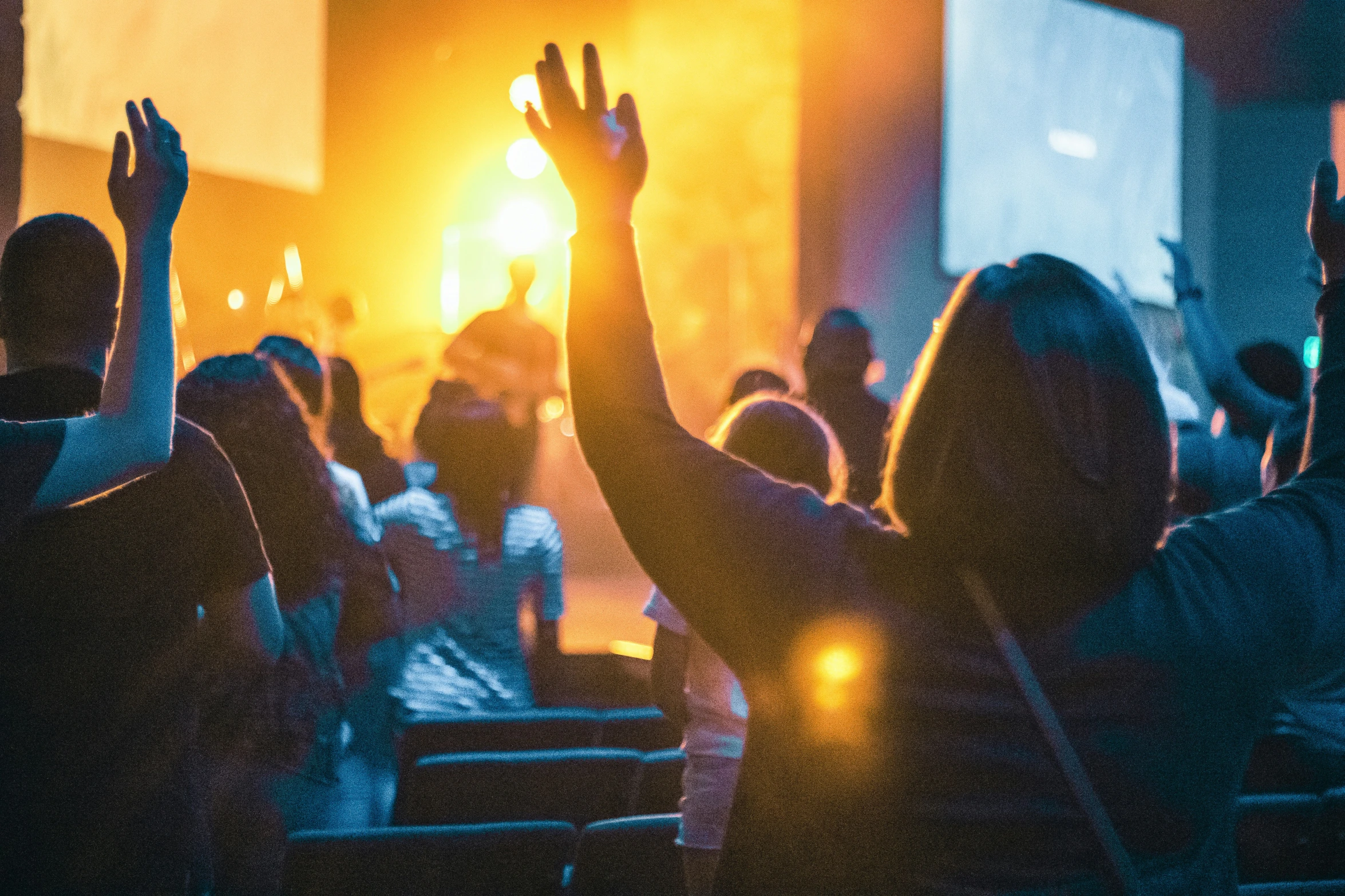 several people raising their hands at an event