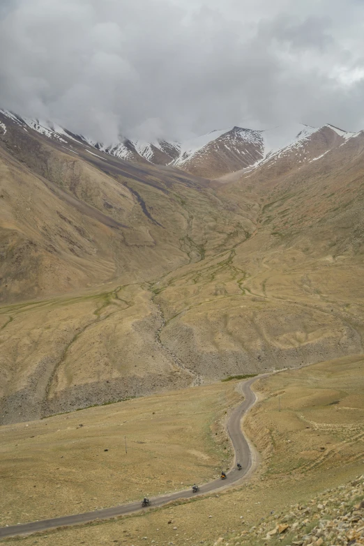 four vehicles traveling down a road in the mountains