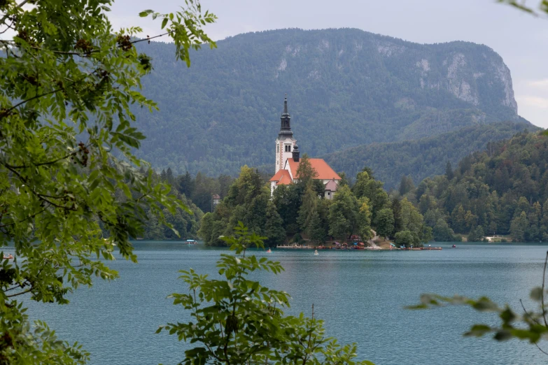 a church is sitting on top of the hill next to water