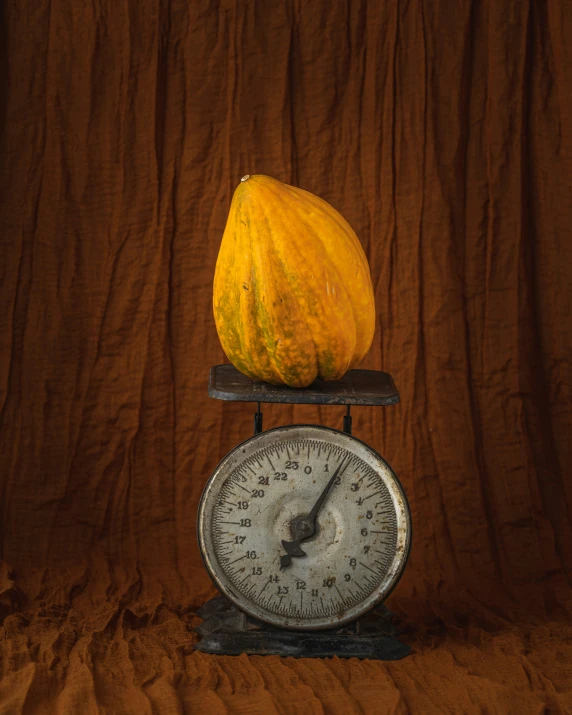 a yellow pumpkin sitting on top of an old weight scale