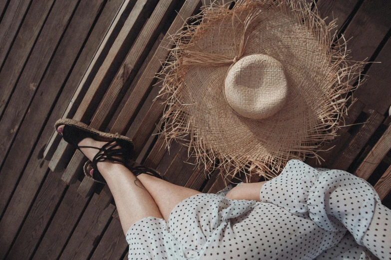 a girl in a dress with heels laying on the floor wearing a straw hat