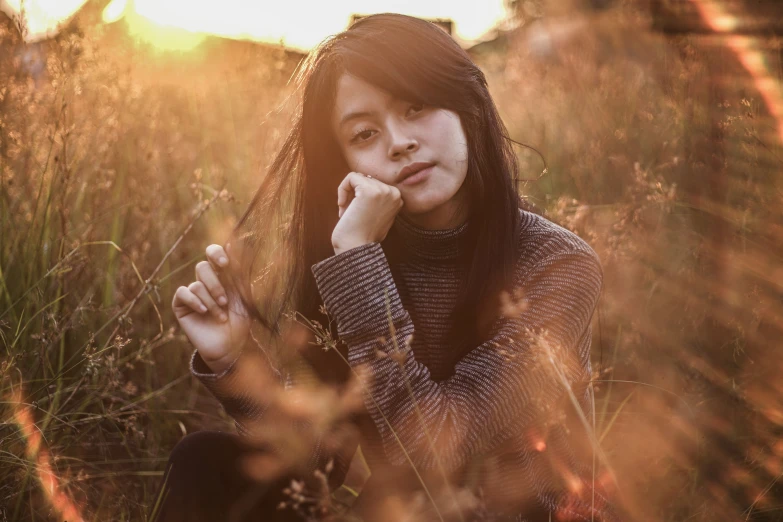 a girl is sitting on some grass and posing for a po