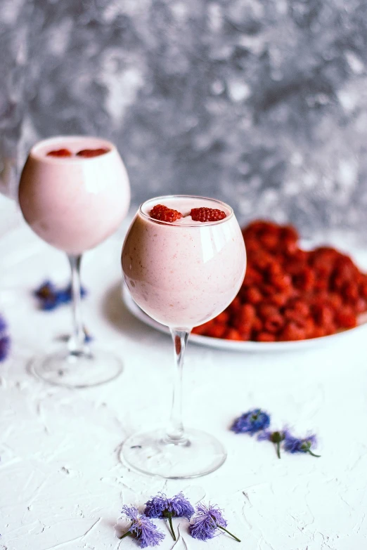 two glasses of raspberry chiquit sitting next to some flowers