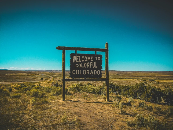 a welcome sign in a remote area under a blue sky