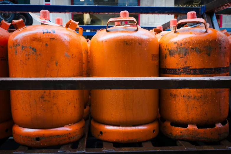 several orange gas bottles sitting next to each other