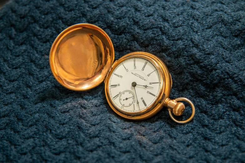 a pocket watch is laying on the blue blanket