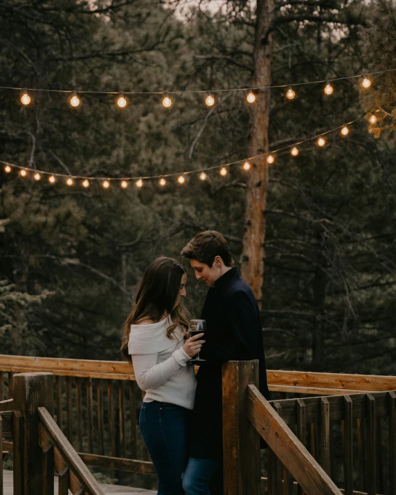 the engaged couple is hugging and enjoying wine