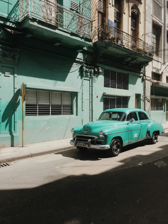 an old car parked on the side of a road in front of a tall building