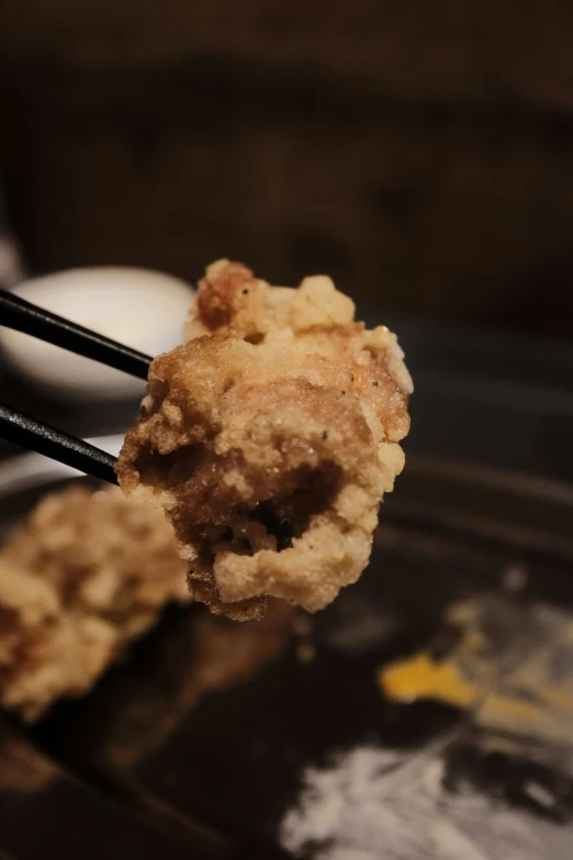 there is a small fried chicken that is holding in her chopsticks