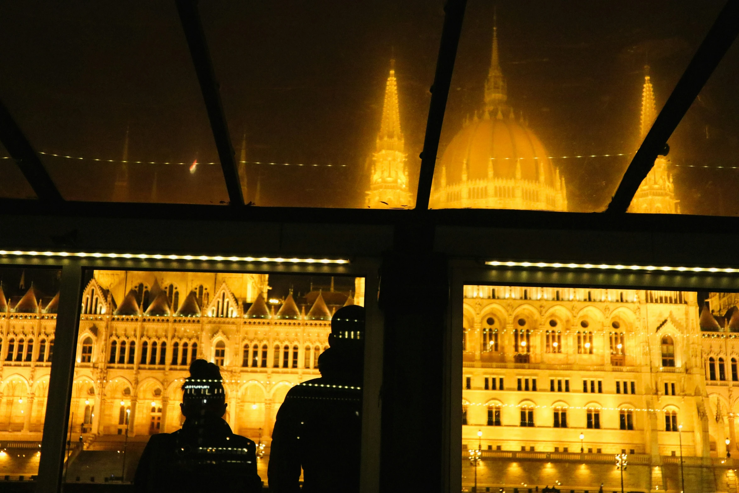 the building is illuminated and behind it is a couple of silhouettes