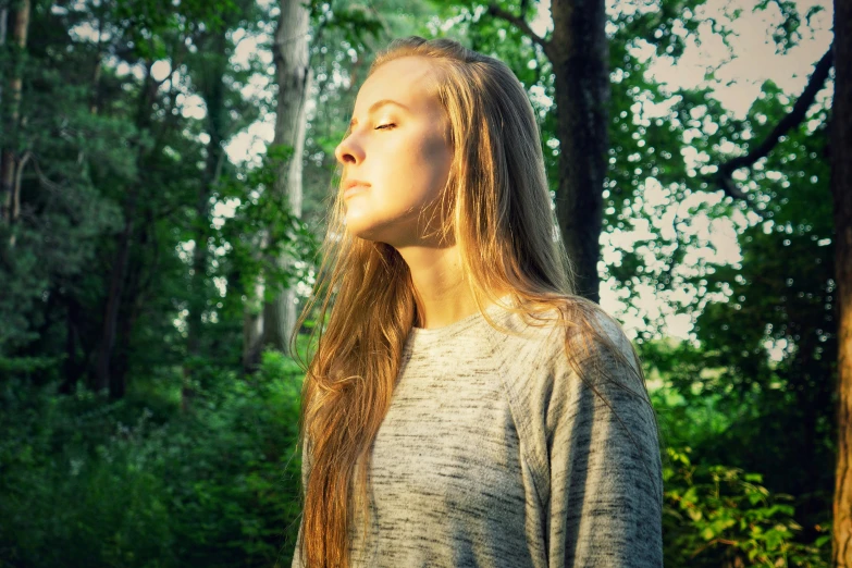 young woman in the forest looks up from her head