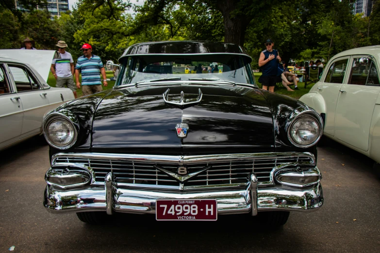 classic cars and people walking around in a line