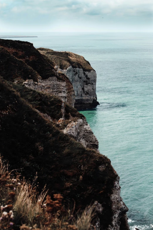 the cliff has a red boat out in the water