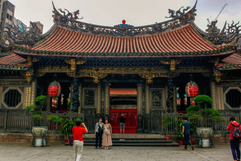 two people and one is standing in front of a chinese building