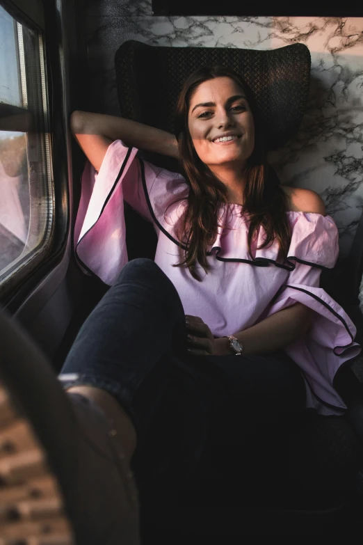 a woman laying on the seats of a train smiling