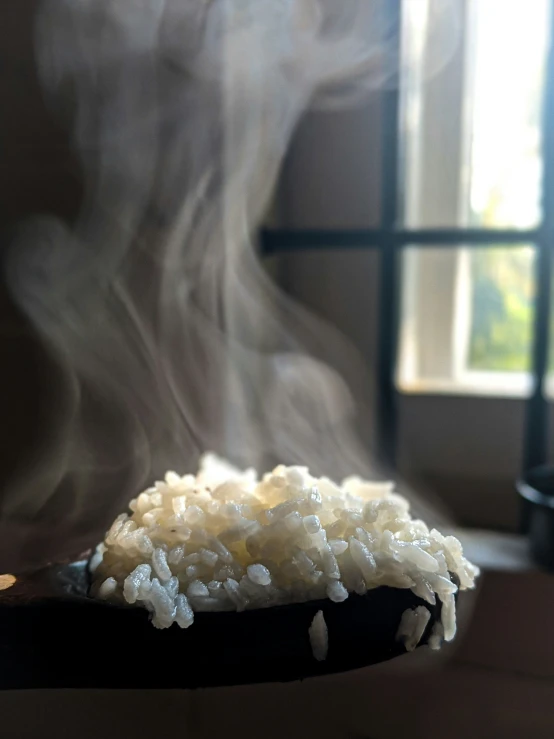 a spoon filled with white rice is next to some smoke