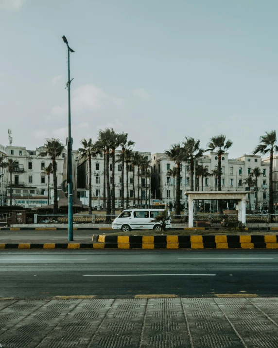 an old building is seen along a street lined with palm trees