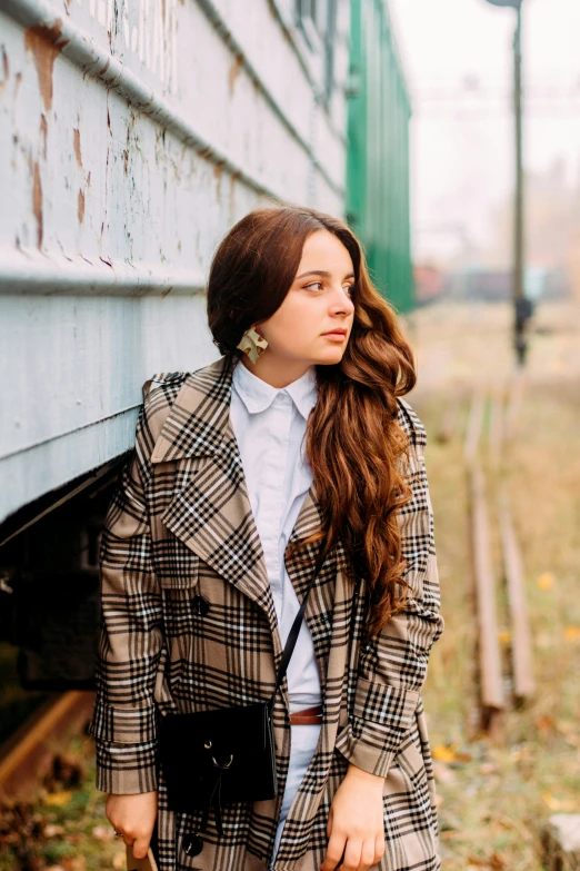 a woman leaning against a wall while standing next to a train