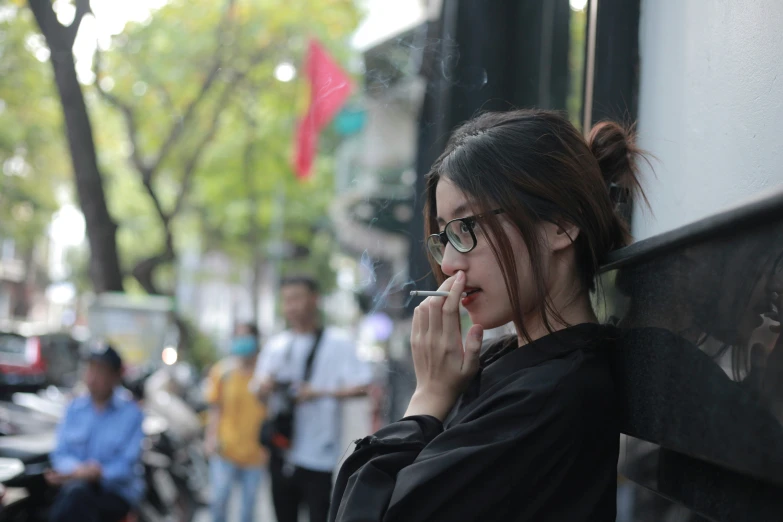 woman on cellphone sitting in wall smoking cigarette