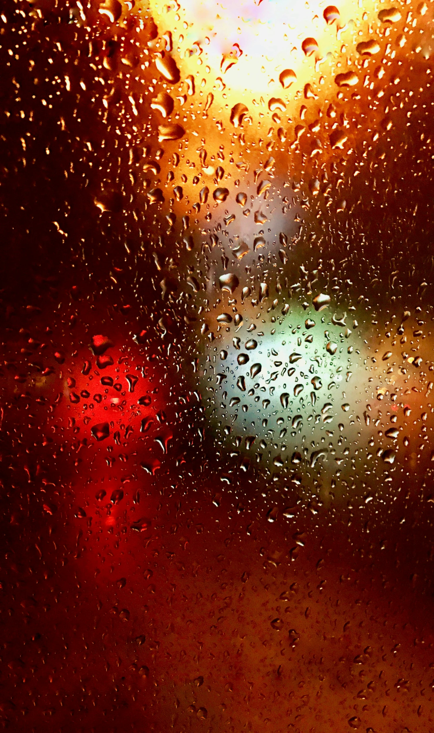 close up s of rain drops on window with red traffic lights