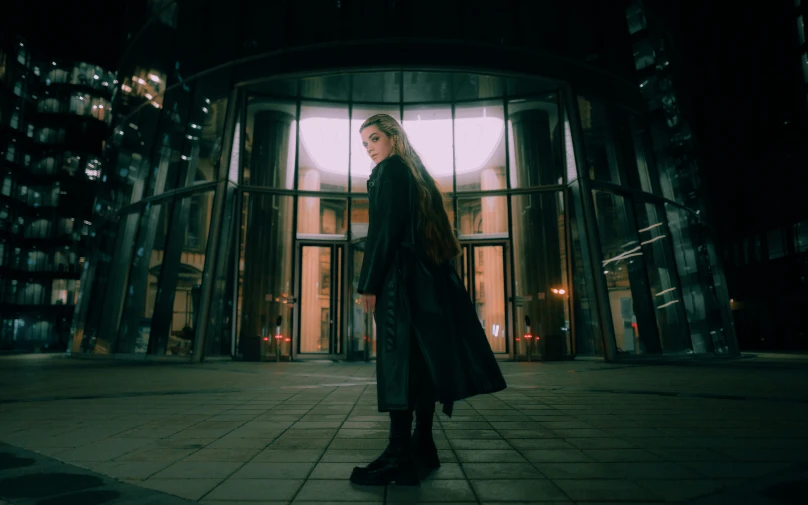 a woman standing alone in front of a large window