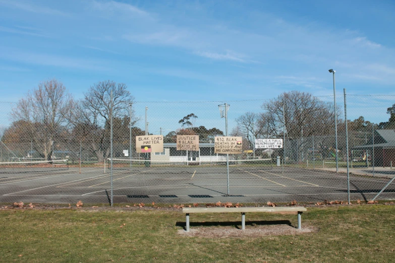 empty, fenced parking lot with trees and buildings