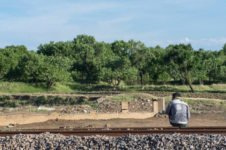 a person looking over a dirt field from a rail road track