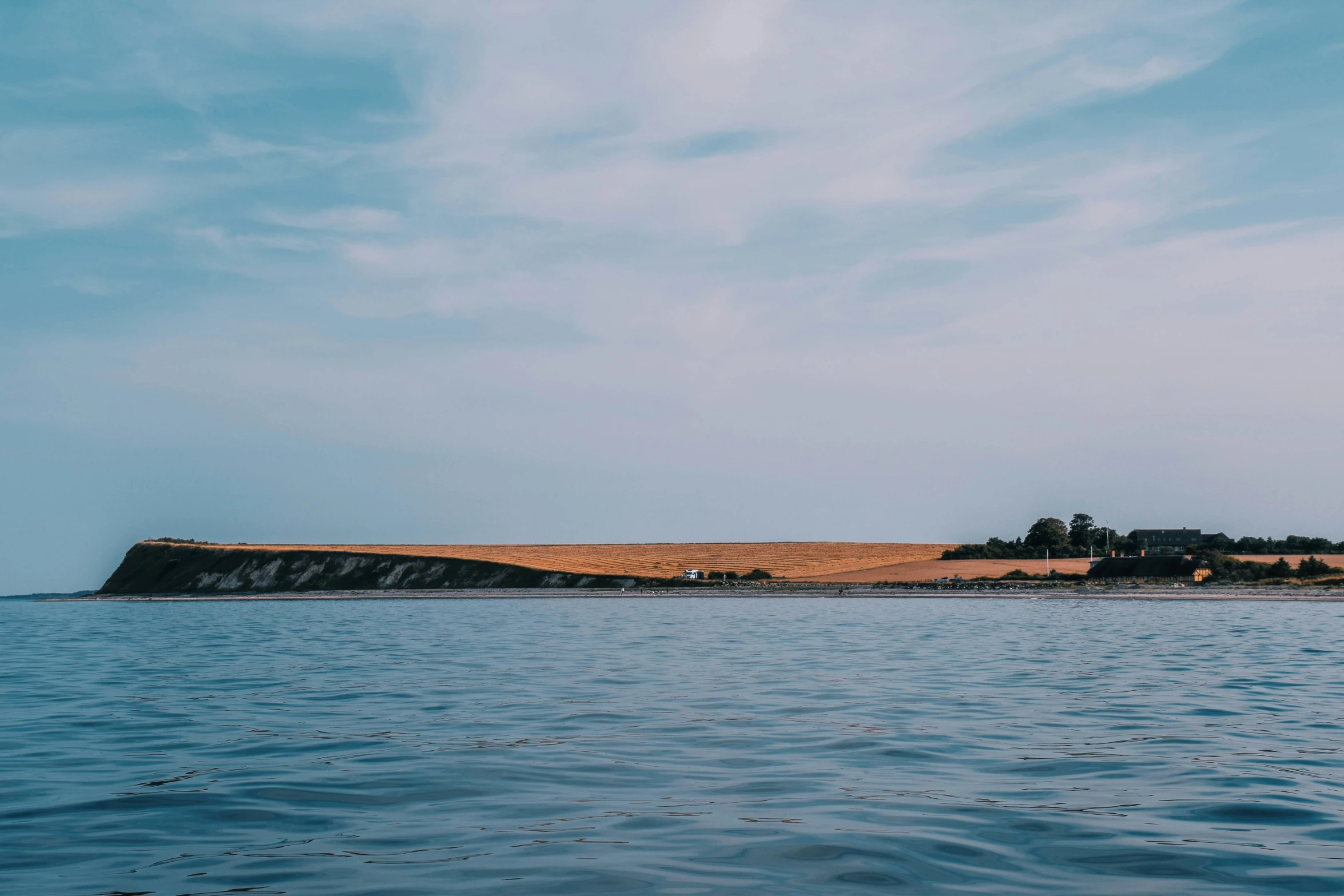 the view of an island with trees, blue ocean water and an airplane flying low in the sky