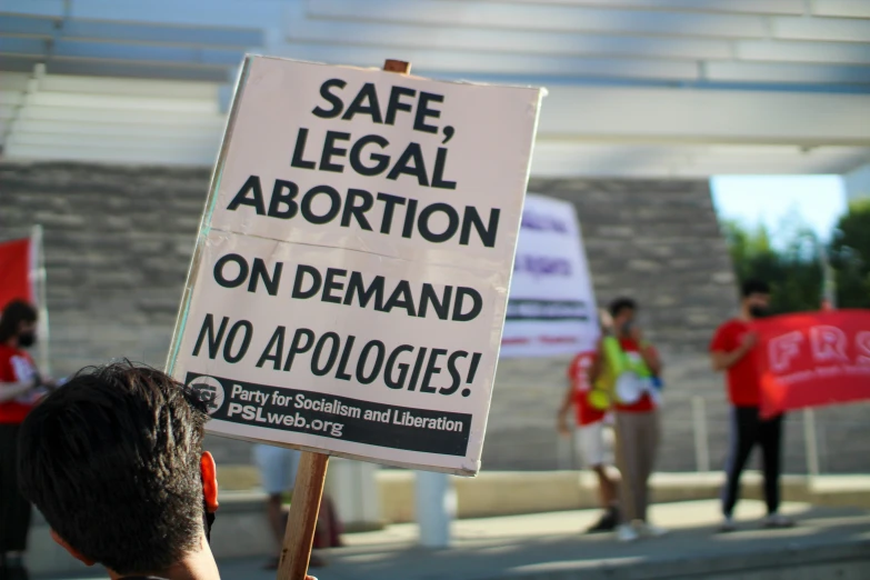 a sign in front of people that is protesting