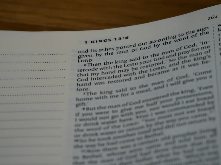 an open book on wooden table with verse written in it