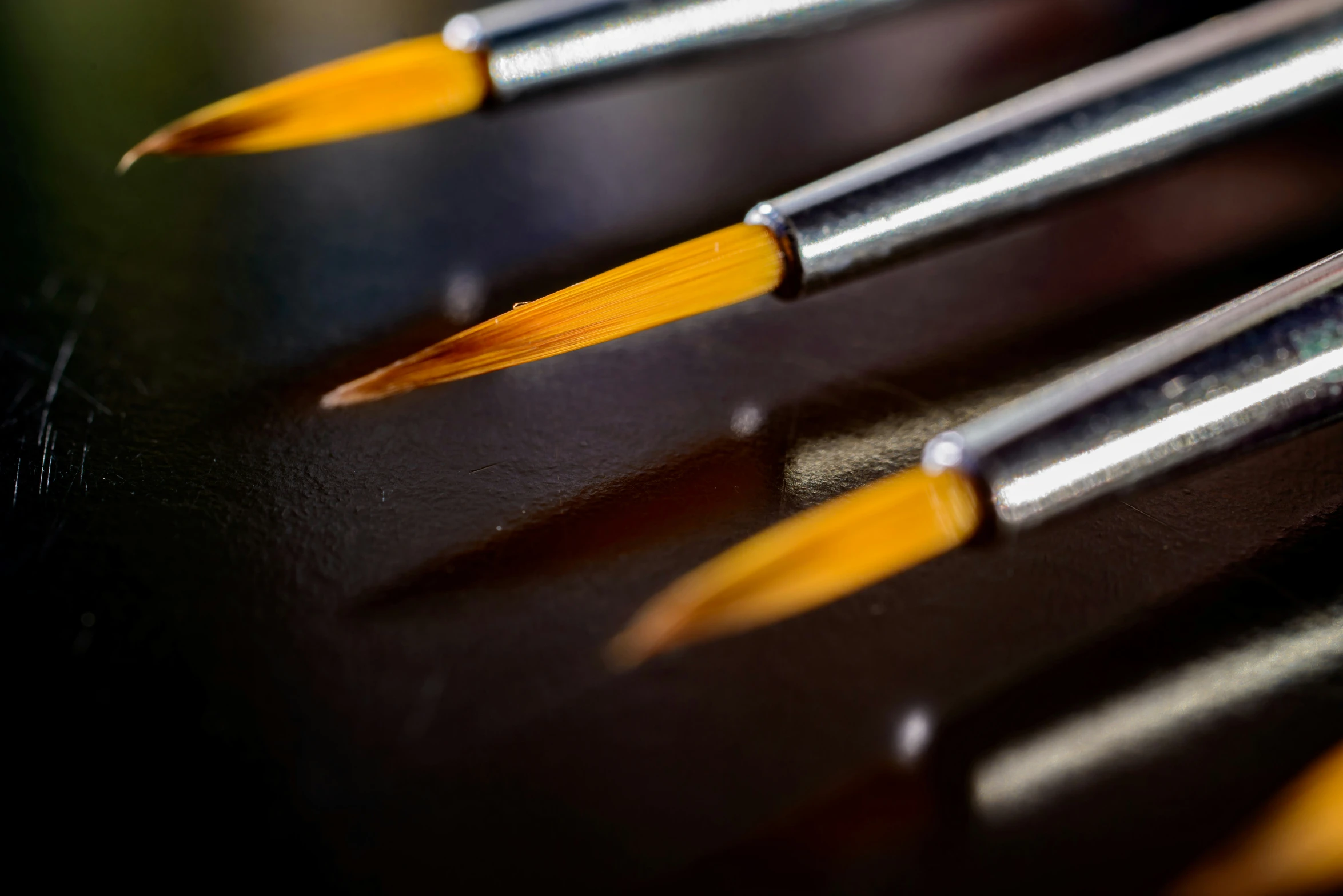 five artistic pencils lined up on a desk