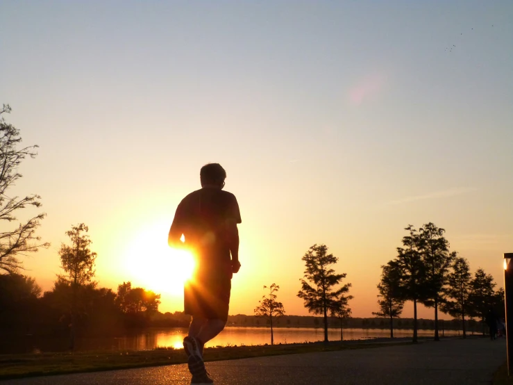 man jogging along a path with the sun rising behind him