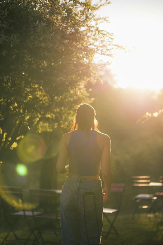 back view of a woman standing in an open area with the sun setting on the other side