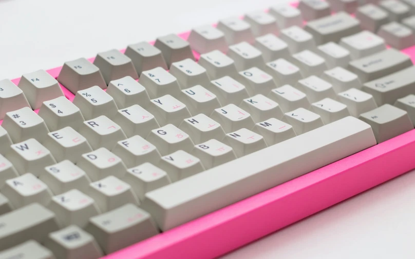 a pink keyboard and white keys on a white desk