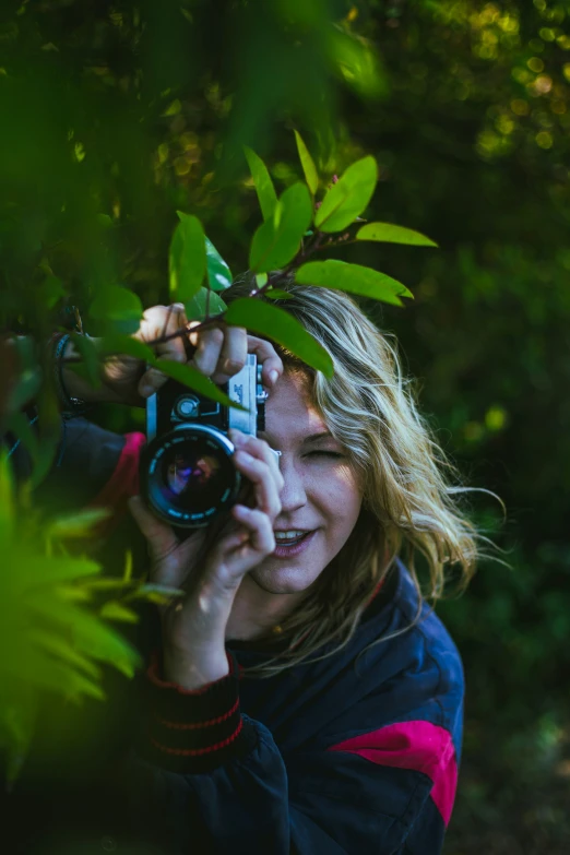 woman holding camera while in a wooded area