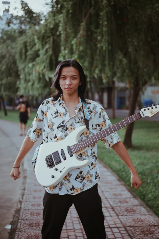 a young man posing holding a guitar in his hand