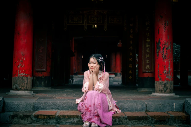 a girl sitting on steps outside wearing a pink dress