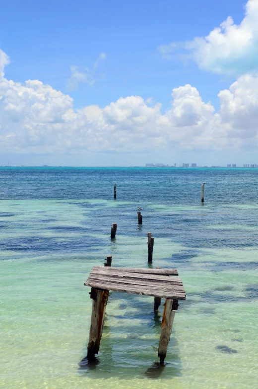 a long wooden bench sitting in the ocean