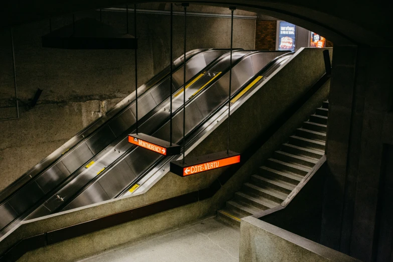 escalator at a subway station at night with orange signs