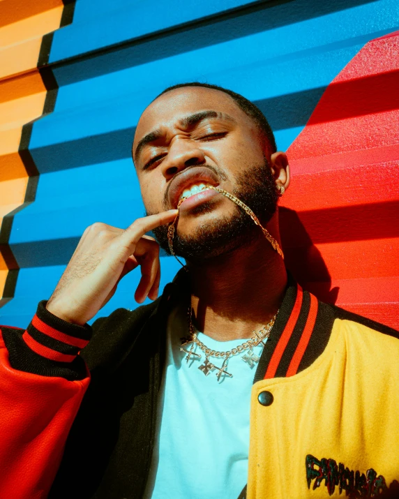 a man standing against a colorful background holding his hand up to his face