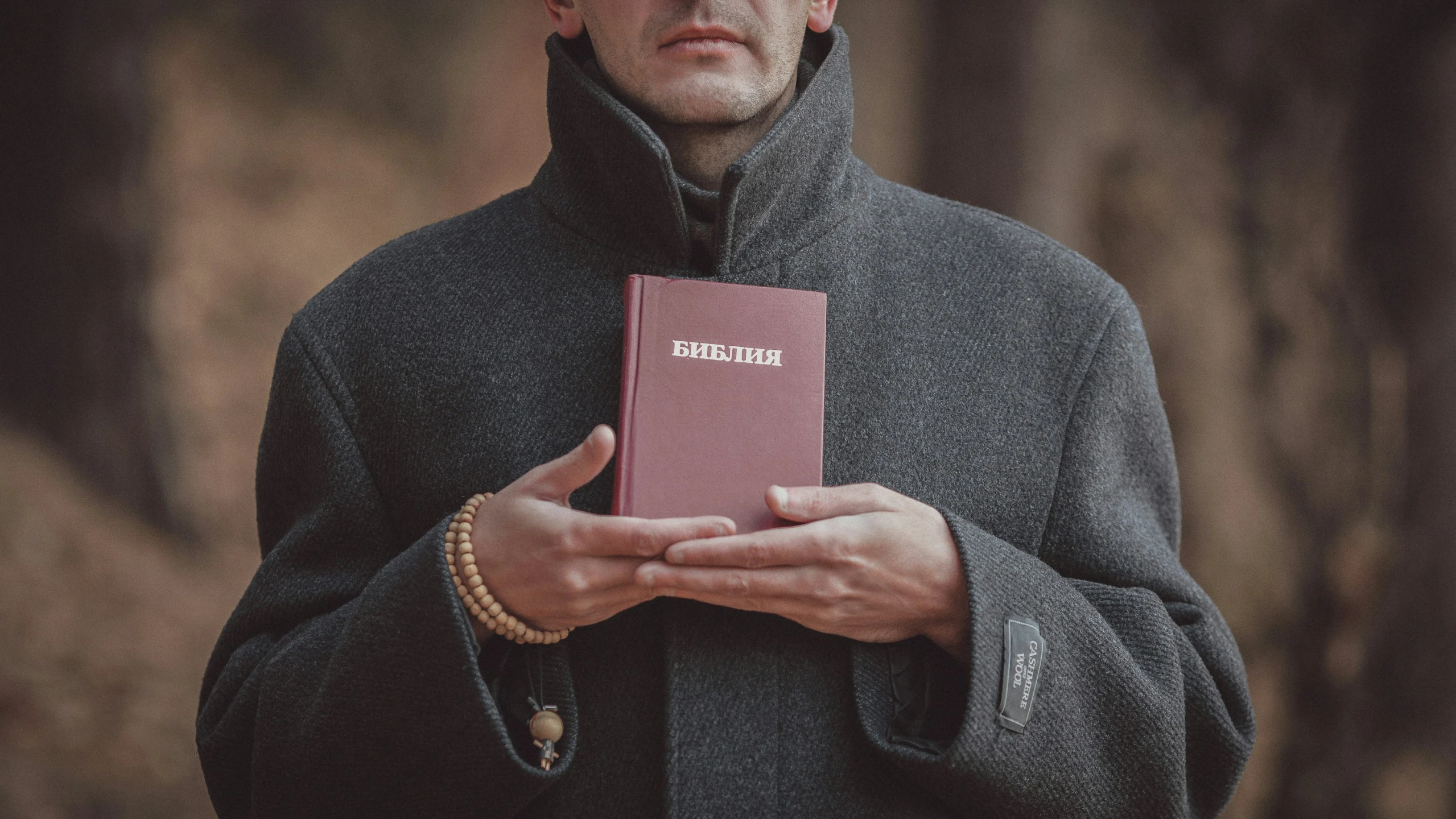 man in winter coat holding a passport looking at camera