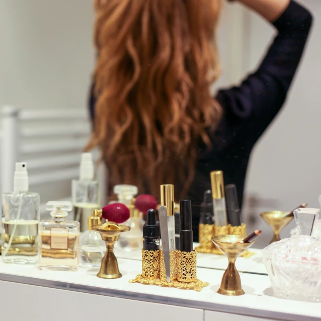 a woman looking at some bottles and gold vases