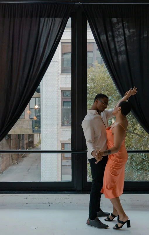 couple in orange dress dancing with window view