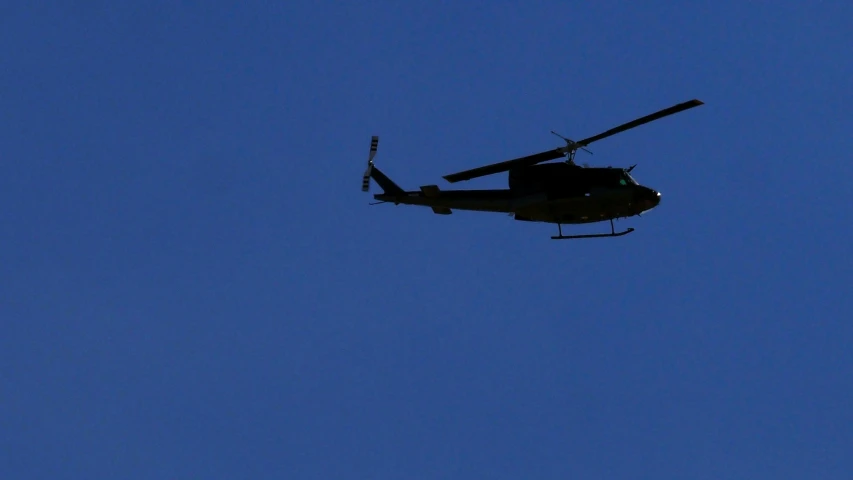 a military helicopter flies in the sky